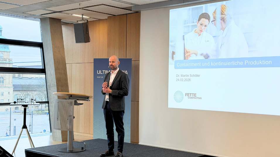 Dr. Martin Schöler stellt sich auf der Bühne vor und redet zum Publikum. Er hält seinen Vortrag zu Containment und kontinuierliche Produktion