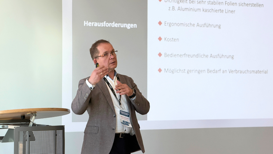 Reiner Lemperle trägt seinen Vortrag auf der Bühne vor und redet über Feststoff-Handling von flexiblen Großgebinden bei Berücksichtigung von Containment Anforderungen 