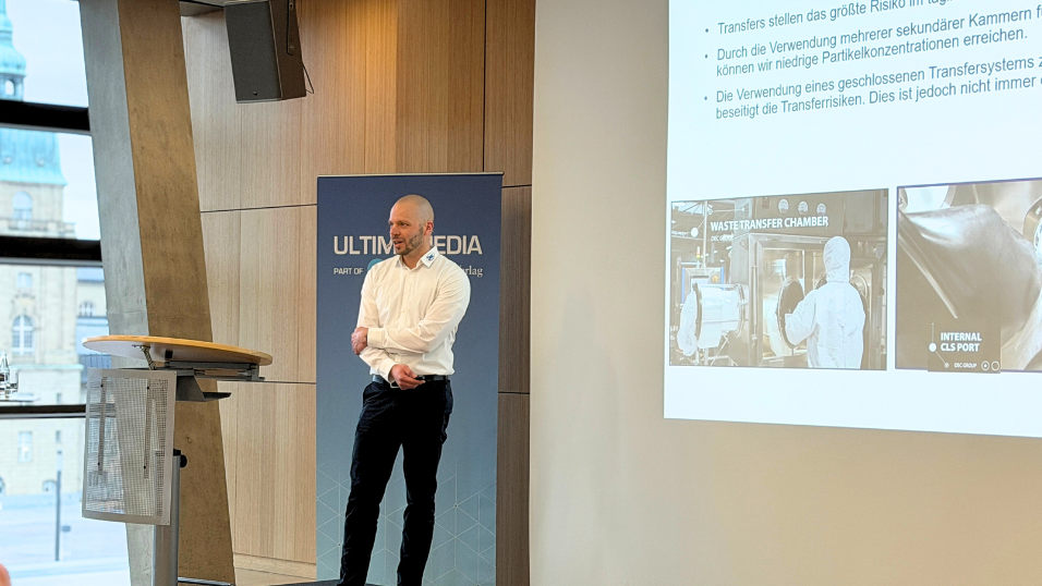 Tobias Behmenburg von DEC Deutschland GmbH steht auf der Bühne und trägt seine Vortrag zum Thema Prozessintegration in Isolatoren vor. Er redet zum Publikum